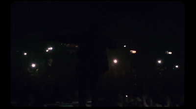 a man standing in front of a crowd at night