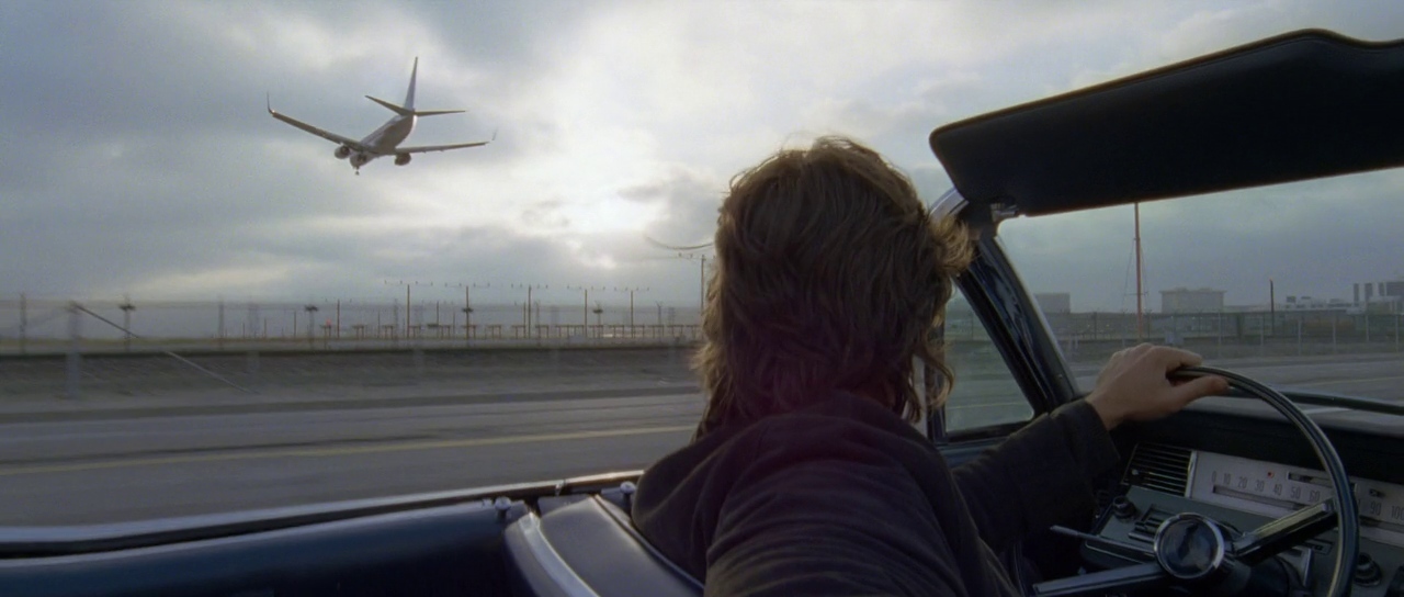 a person in a car watching an airplane take off