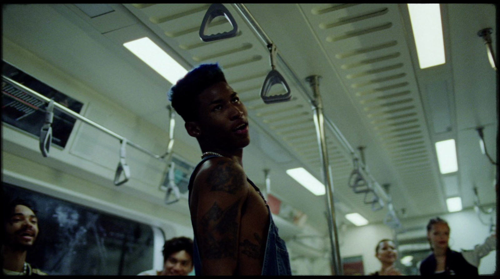 a man with tattoos on his chest standing in a subway car