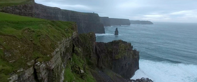 a large cliff near the ocean on a cloudy day