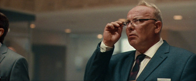 a man in a suit and tie holding a pair of glasses