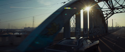 a car driving on a bridge with the sun shining