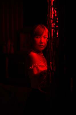 a woman standing in a dark room with a red light