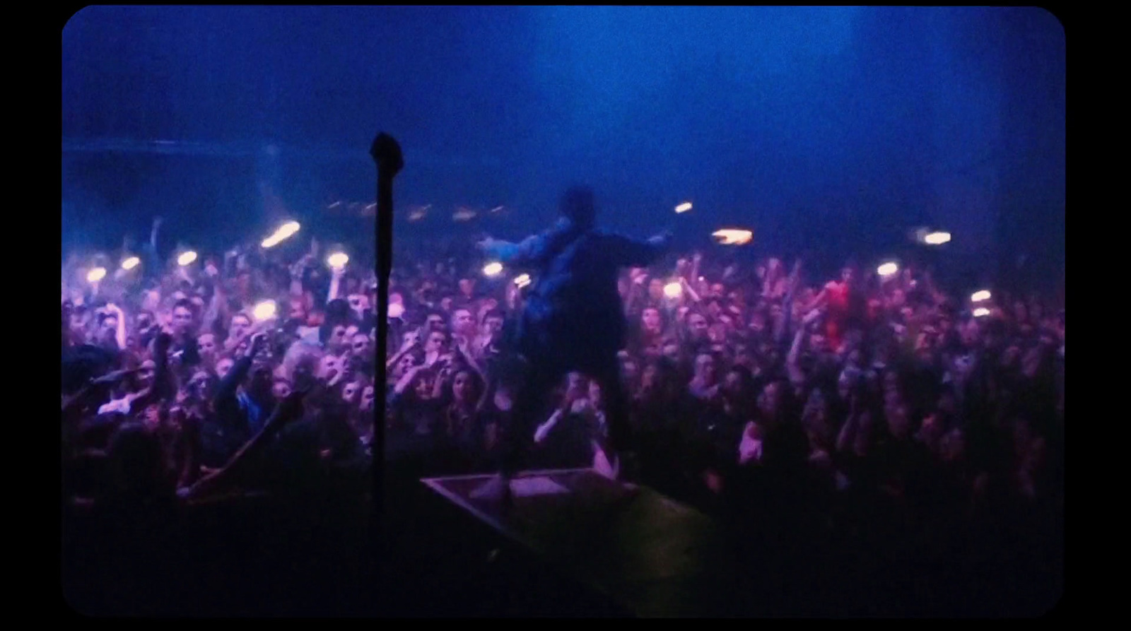 a man standing on top of a stage in front of a crowd