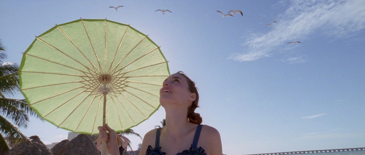 a woman standing on a beach holding a green umbrella