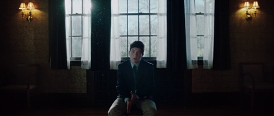 a man sitting on a chair in front of two windows