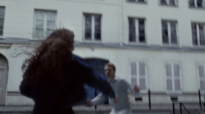 a blurry photo of a man and a woman running in front of a building