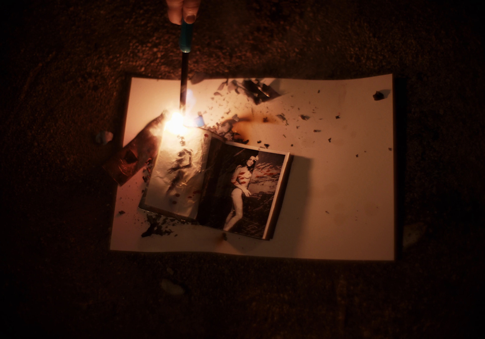 a person holding a lit candle over a picture on a piece of paper