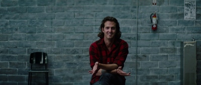 a man sitting on a stool in front of a brick wall