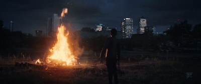 a man standing in front of a fire in a field