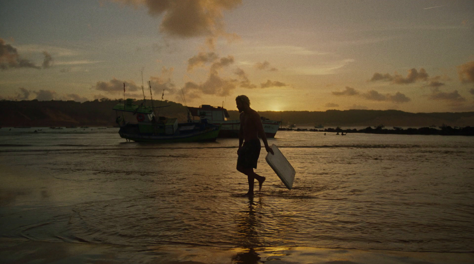 a man holding a surfboard walking into the ocean