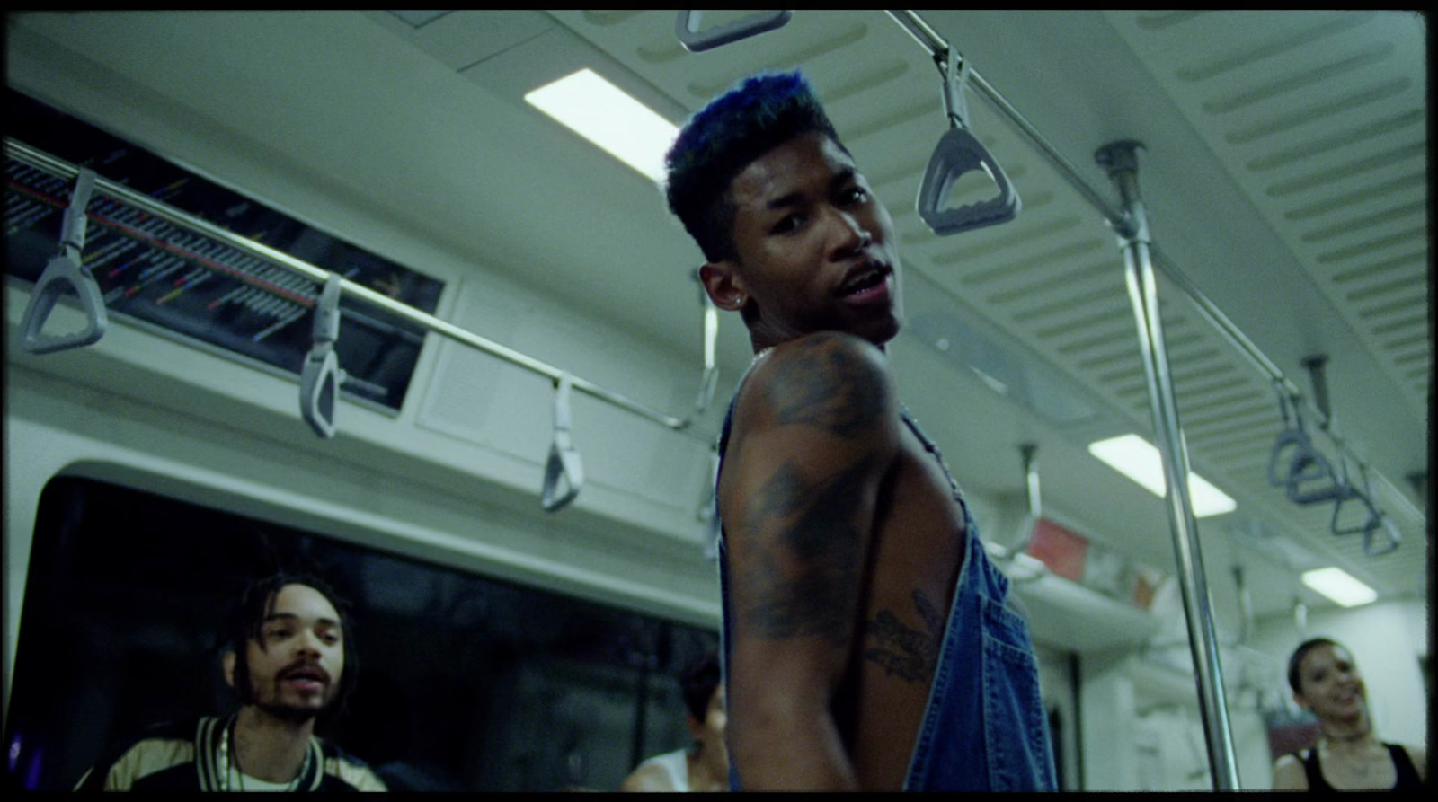 a man with tattoos standing in a subway car