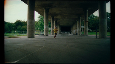 a man is running under a bridge in a parking lot