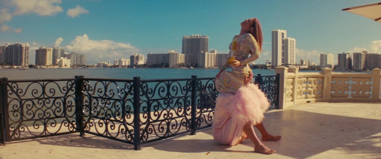 a woman in a pink dress standing on a balcony