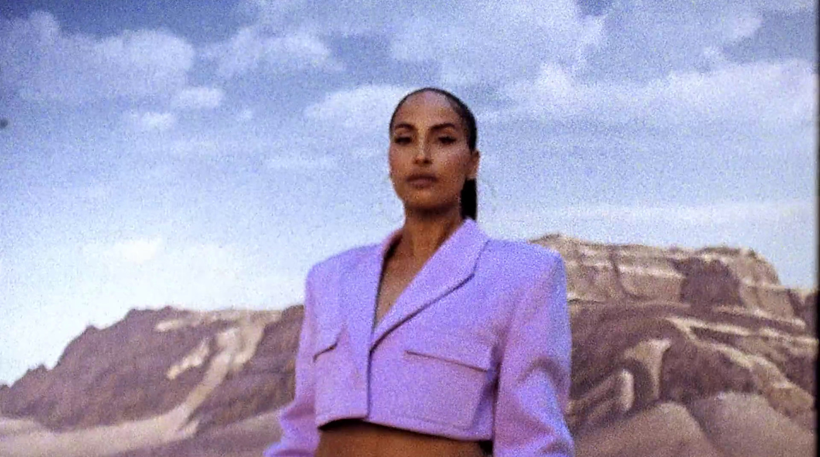 a woman in a purple suit standing in front of a mountain