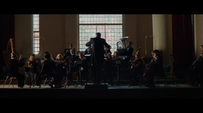 a conductor and orchestra in a large room