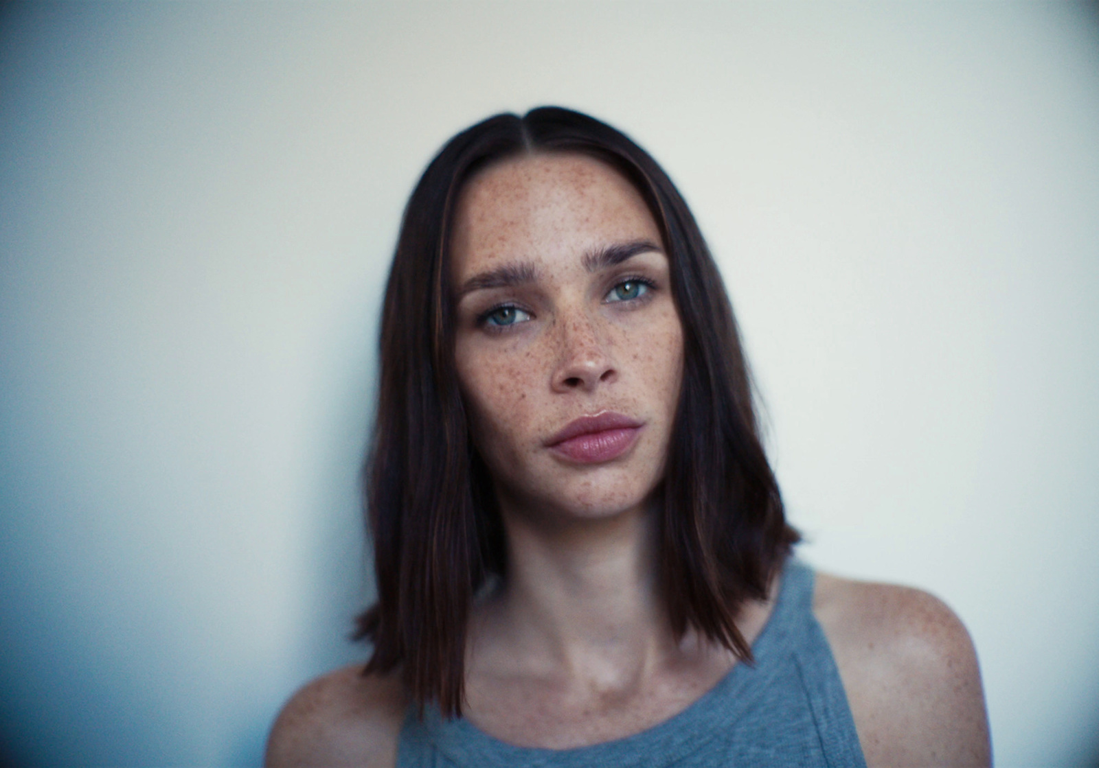 a woman with freckled hair and a blue tank top