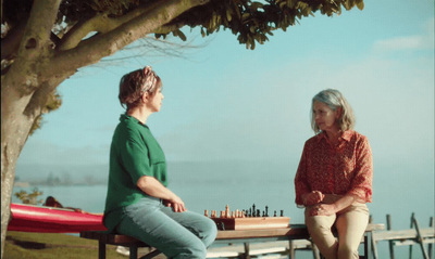 two women sitting at a picnic table playing chess