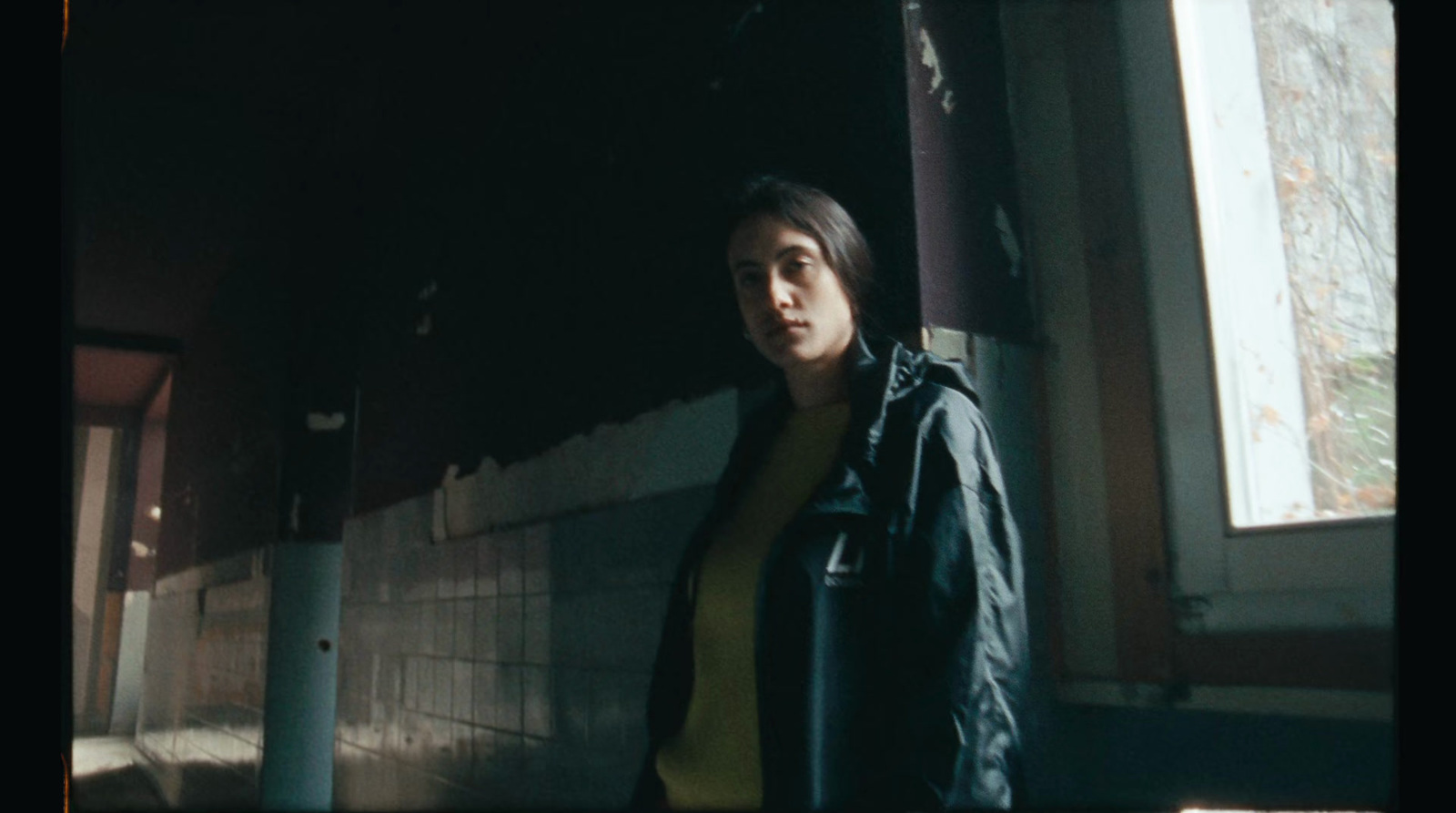 a woman standing next to a wall in a dark room