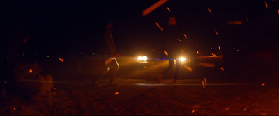 a couple of people standing next to a car at night