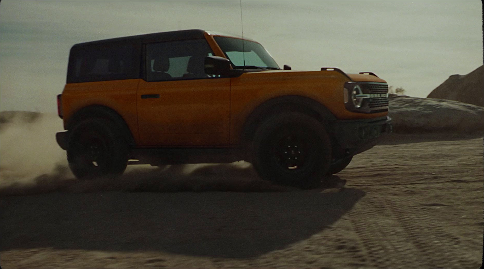 an orange truck driving down a dirt road