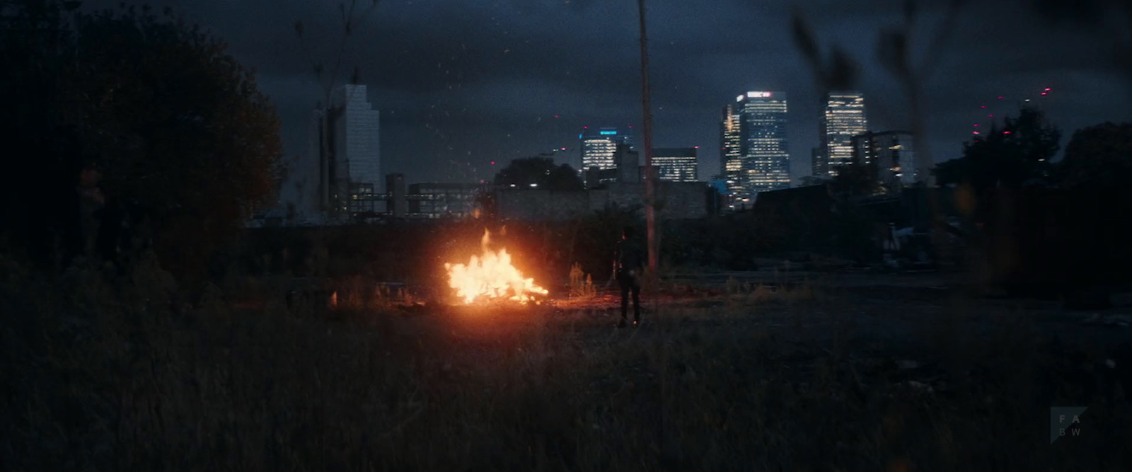 a fire in the middle of a field with a city in the background