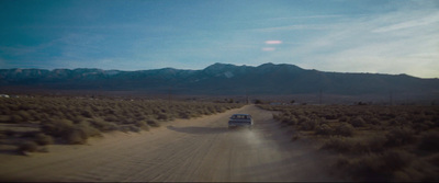 a truck driving down a dirt road in the desert