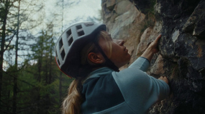 a woman climbing up the side of a mountain