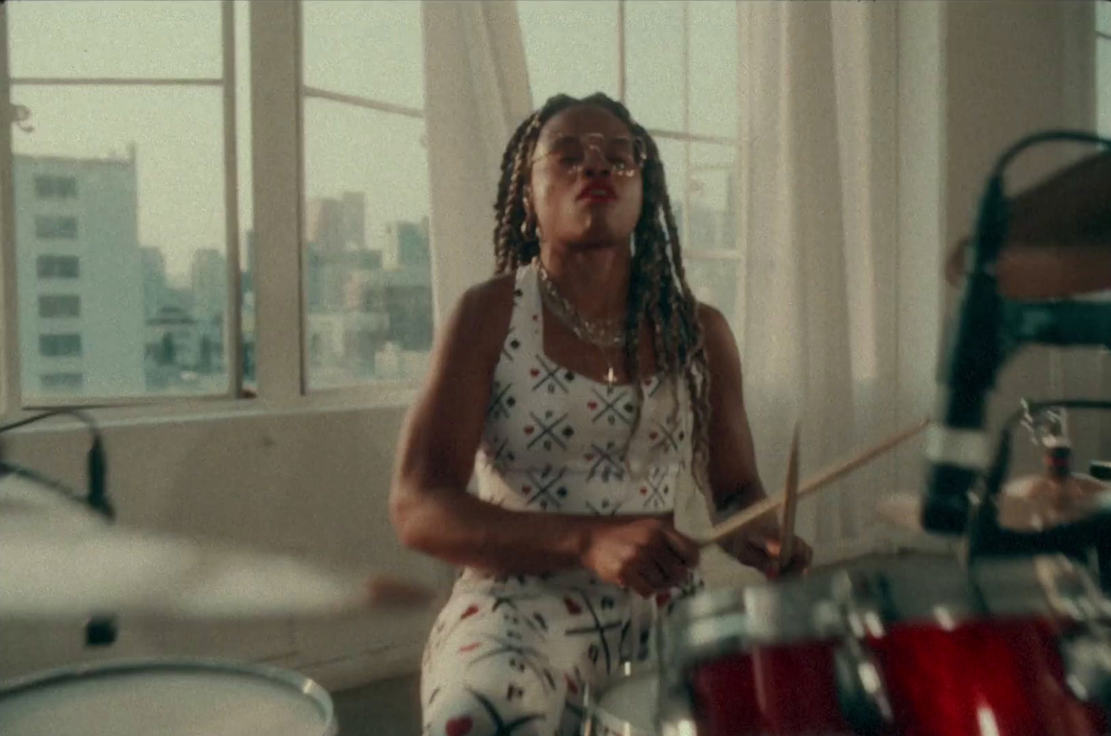 a woman with dreadlocks playing drums in a room