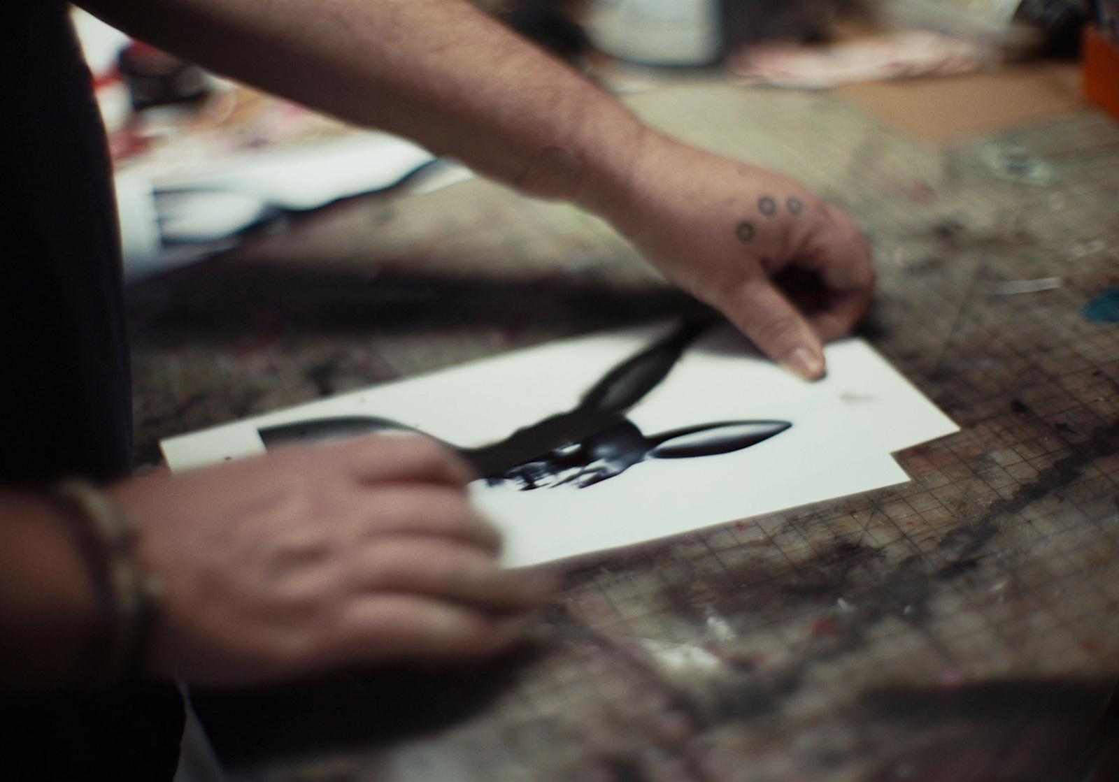 a person holding a pair of scissors over a piece of paper