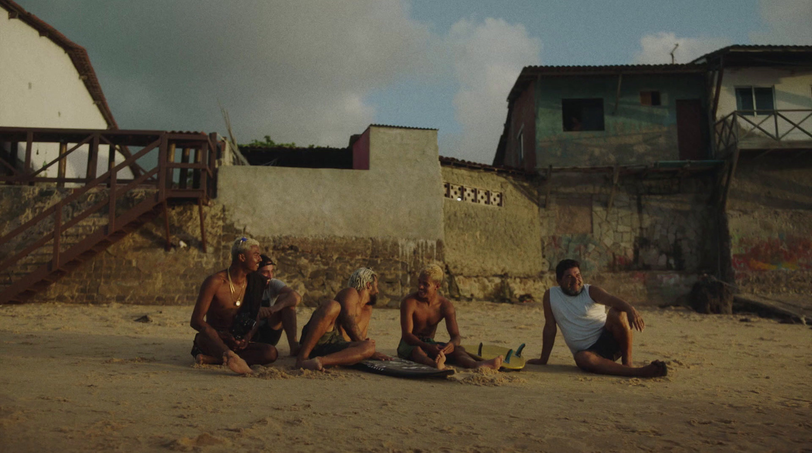 a group of men sitting on top of a sandy beach