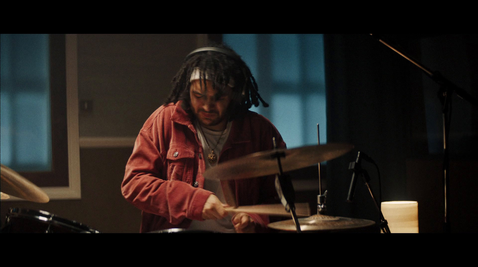 a man with dreadlocks playing drums in a recording studio