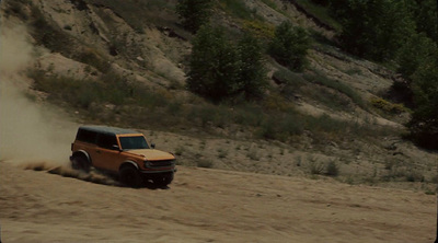 a jeep driving down a dirt road next to a hill