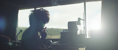 a man sitting in front of a window talking on a cell phone