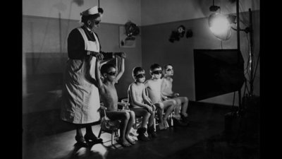 a black and white photo of a man standing in front of a group of children