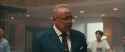 a man in a suit and tie walking down a hallway