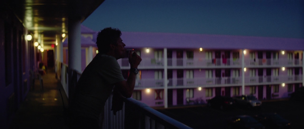 a man standing on a balcony smoking a cigarette