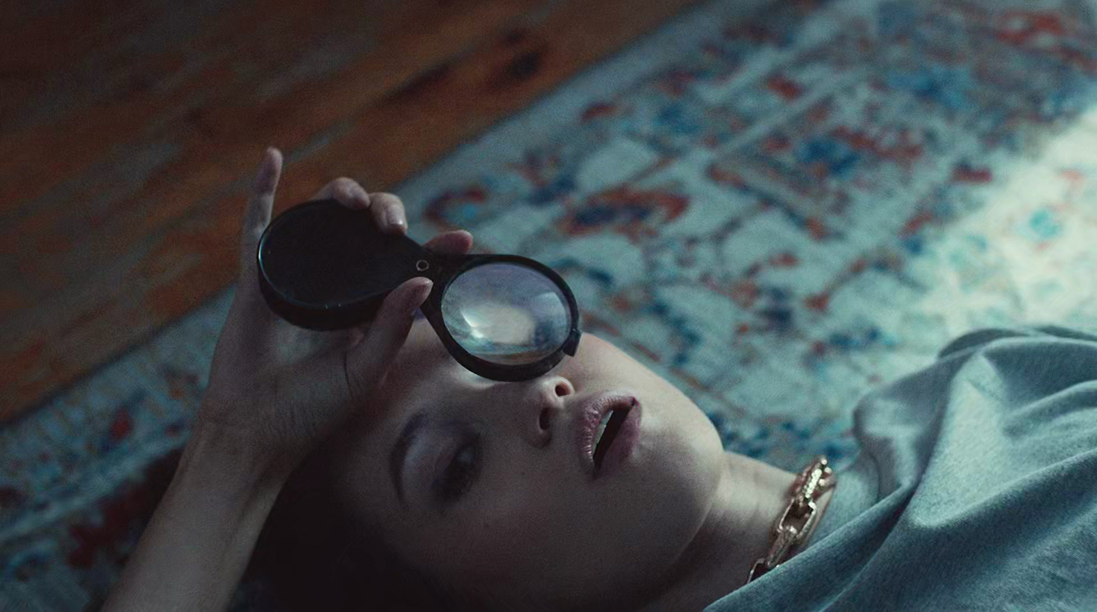 a woman laying on a rug looking through a magnifying glass