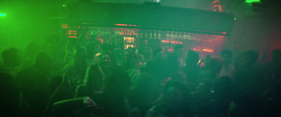 a crowd of people standing around a bar at night