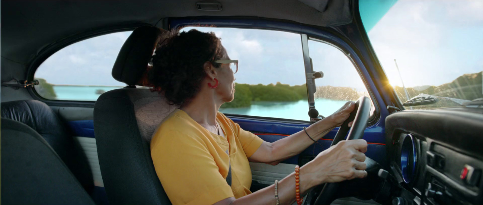 a woman sitting in a car with a steering wheel