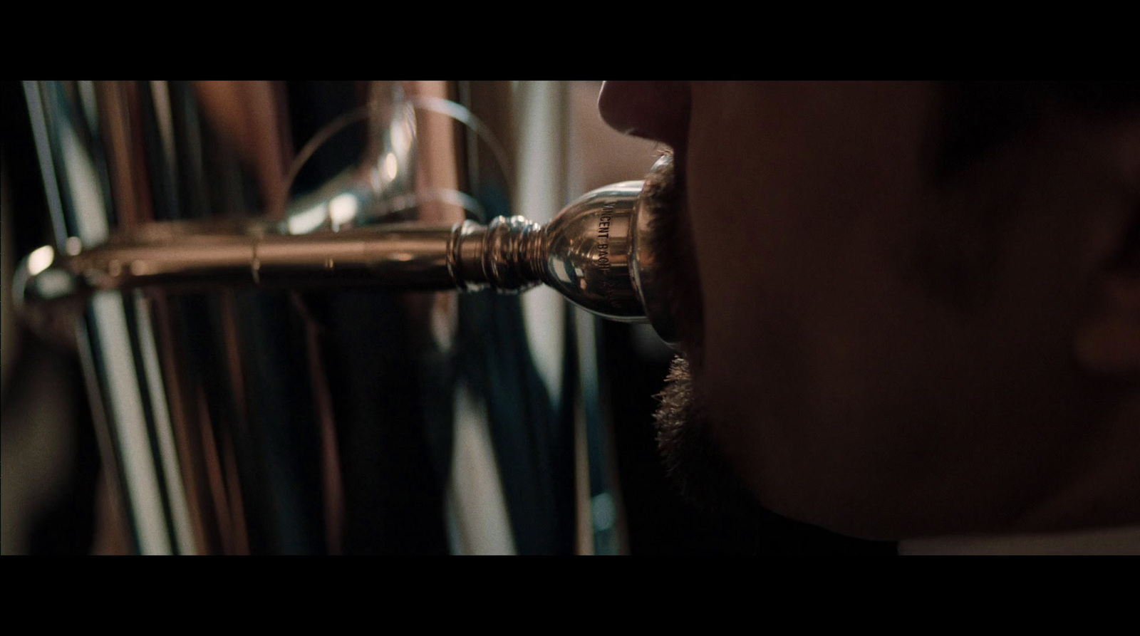 a close up of a person's face with a metal object in the background