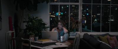 a woman sitting at a table in front of a laptop computer