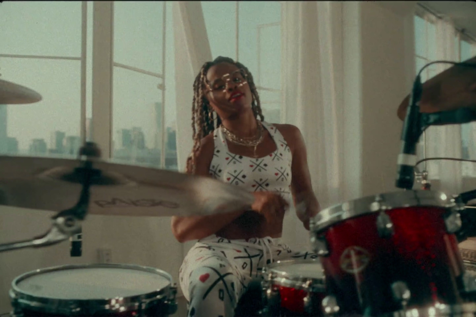 a woman with dreadlocks playing drums in a room