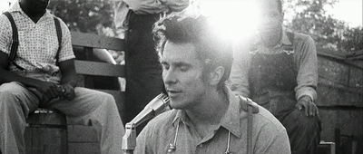 a black and white photo of a man sitting on a bench