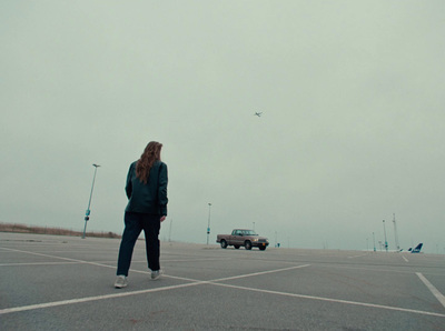 a woman standing in a parking lot next to a car