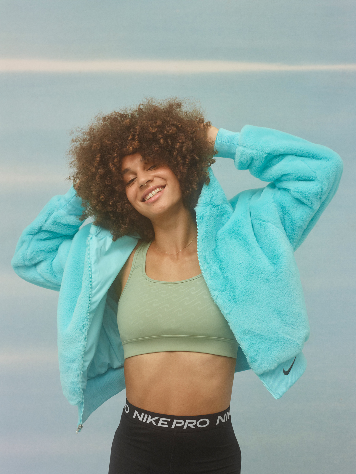 a woman with curly hair wearing a blue jacket