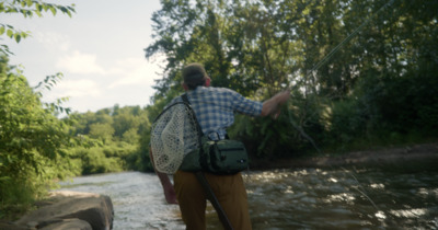 a man standing on a river holding a fishing rod