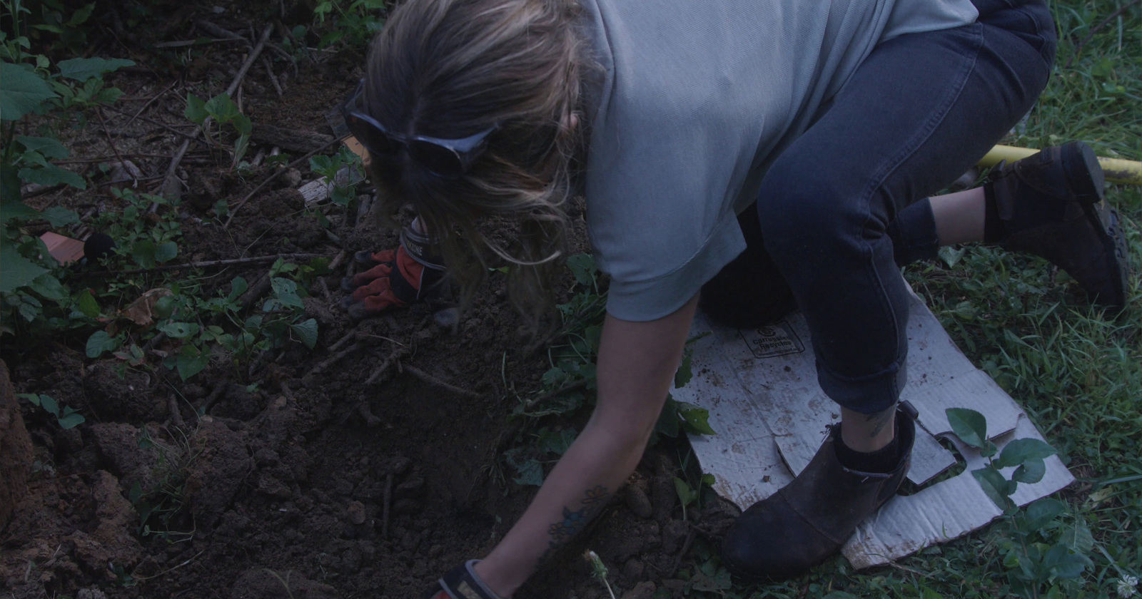 a woman digging in the ground with a garden tool