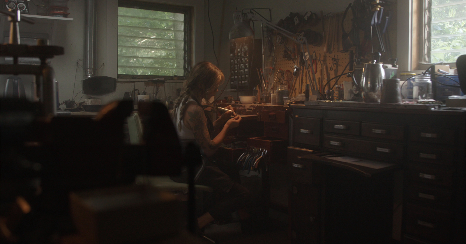 a woman sitting in a room with lots of clutter