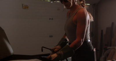 a woman in a garage with a pair of gloves on